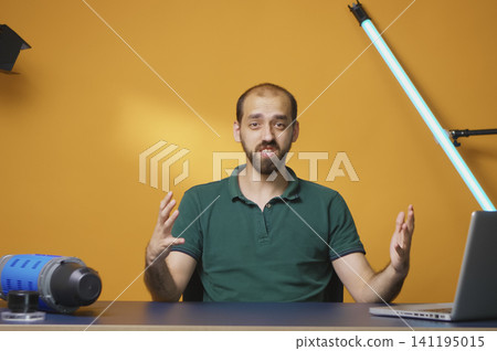 Excited vlogger records a video with professional gear for a social media audience, creating online review content in a studio setup. 141195015
