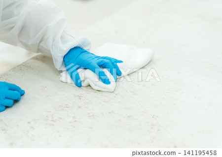 戴著丁腈手套的手正在擦拭桌子 戴著丁腈手套的手正在擦拭桌子 141195458
