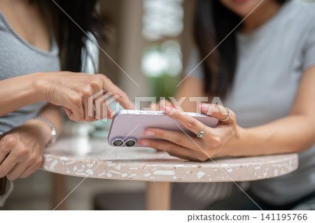 Close up detail of an Asian woman hand pointing finger at a purple smartphone screen. Close up detail of an Asian woman hand pointing finger at a purple smartphone screen. 141195766