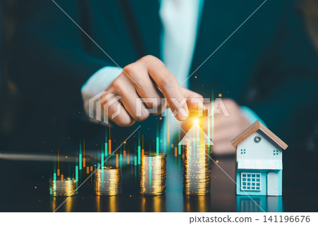 Close up of businessman hand stacking gold coins with growing stock market graph and small house model, real estate and financial concept. Close up of businessman hand stacking gold coins with growing stock market graph and small house model, real estate and financial concept. 141196676