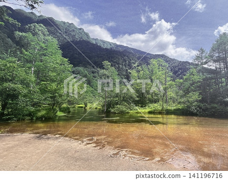 上高地田代池的夏季景色,清澈的池水中可以看到紅褐色的河床。 上高地田代池的夏季景色,清澈的池水中可以看到紅褐色的河床。 141196716