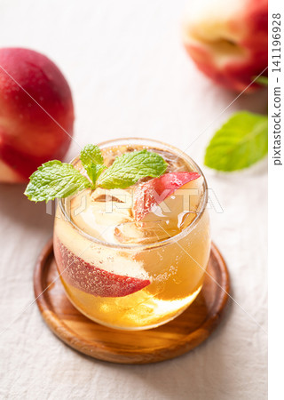 Iced peach soda mocktail in a glass with fresh mint leaves and juicy peach slices, summer drink Iced peach soda mocktail in a glass with fresh mint leaves and juicy peach slices, summer drink 141196928