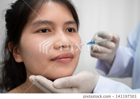 Asian woman receiving botox filler beauty injection. Asian woman receiving botox filler beauty injection. 141197301