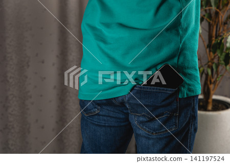 Man holds smartphone in pocket of jeans in casual setting at home 141197524