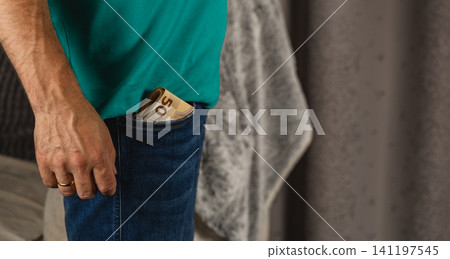 Man holds phone in hand with cash in pocket in casual setting Man holds phone in hand with cash in pocket in casual setting 141197545