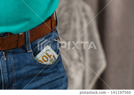 Man wears denim jeans with cash visible in pocket during casual moment 141197560