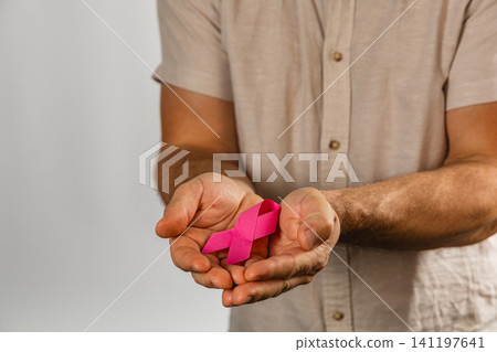 Man holds pink ribbon symbol for health awareness and support Man holds pink ribbon symbol for health awareness and support 141197641