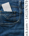 Closeup of denim jeans with a pocket holding a white card 141197679