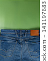 Denim jeans with pocket details on a green background 141197683