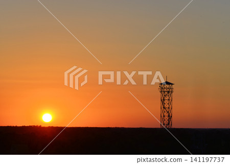 Silhouette of an observation tower against a vibrant orange sunset sky Silhouette of an observation tower against a vibrant orange sunset sky 141197737