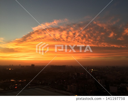 Vibrant orange sunset clouds over a city skyline at dusk Vibrant orange sunset clouds over a city skyline at dusk 141197738