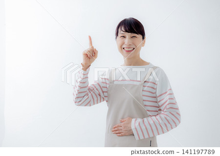 一位身穿圍裙的女士指著某人。 141197789
