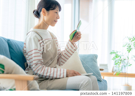 Middle-aged woman looking at her bankbook Middle-aged woman looking at her bankbook 141197809