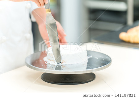 The hands of a pastry chef, cake maker, or confectioner making cakes and Western-style sweets in the kitchen. The hands of a pastry chef, cake maker, or confectioner making cakes and Western-style sweets in the kitchen. 141197821