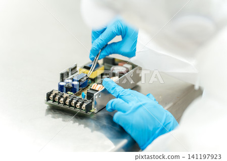 The hands of staff handling precision equipment in a cleanroom The hands of staff handling precision equipment in a cleanroom 141197923