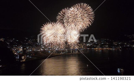 Aerial view of the spectacular fireworks display over the sea illuminating the night view of Atami Onsen town. Aerial view of the spectacular fireworks display over the sea illuminating the night view of Atami Onsen town. 141198321