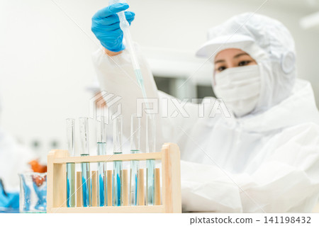 Staff wearing clean suits developing drugs at a pharmaceutical factory or pharmaceutical company 141198432