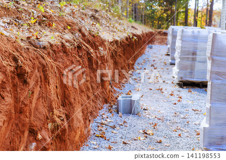 Construction site trench dug and stacked cement block located in wooded area Construction site trench dug and stacked cement block located in wooded area 141198553