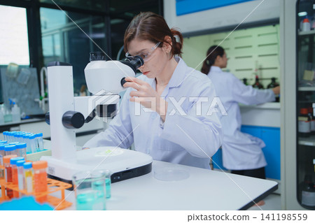 Scientist Analyzing Samples with Microscope in a Laboratory Scientist Analyzing Samples with Microscope in a Laboratory 141198559