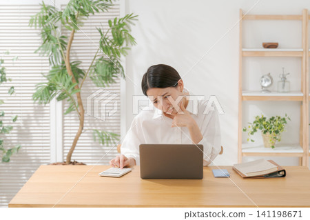 A woman with a worried expression looking at a computer A woman with a worried expression looking at a computer 141198671