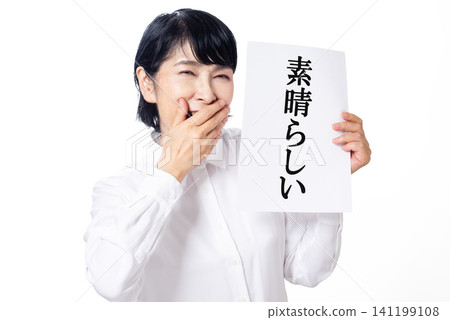 A middle-aged woman in a white shirt is delighted to see a piece of paper that says "Wonderful." A middle-aged woman in a white shirt is delighted to see a piece of paper that says "Wonderful." 141199108