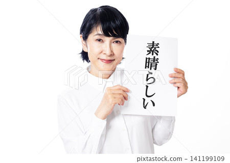 A middle-aged woman in a white shirt smiles, holding a piece of paper with the word "wonderful" written on it in both hands. A middle-aged woman in a white shirt smiles, holding a piece of paper with the word "wonderful" written on it in both hands. 141199109