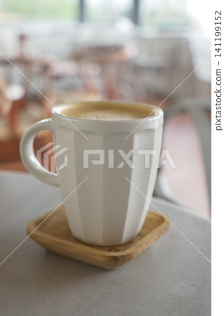 Coffee cup sits on a wooden tray in a cafe Coffee cup sits on a wooden tray in a cafe 141199152