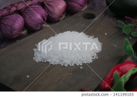 Salt placed on a wooden board with garlic and chilies nearby Salt placed on a wooden board with garlic and chilies nearby 141199185