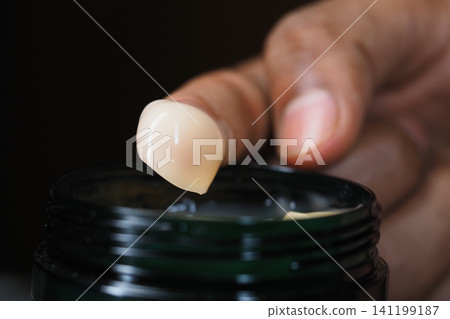 Applying cream from a jar using a finger Applying cream from a jar using a finger 141199187