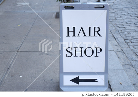 Sign directs to hair shop on city street Sign directs to hair shop on city street 141199205