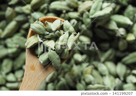 Cardamom seeds in wooden spoon on green background Cardamom seeds in wooden spoon on green background 141199207