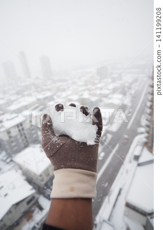 Snowball held high over a snowy city landscape Snowball held high over a snowy city landscape 141199208