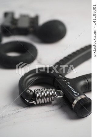 Hand grip strengthener on a flat surface with workout gear Hand grip strengthener on a flat surface with workout gear 141199301