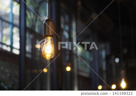 Light bulb hangs from ceiling in a cafe with large windows Light bulb hangs from ceiling in a cafe with large windows 141199322