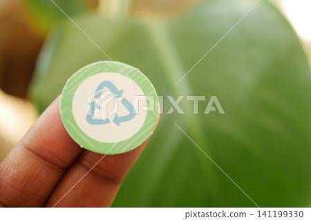 Recycling symbol sticker held by a person in nature Recycling symbol sticker held by a person in nature 141199330