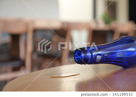 Empty blue bottle on a wooden table in a quiet cafe Empty blue bottle on a wooden table in a quiet cafe 141199331
