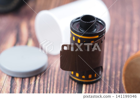 Film roll and canister placed on wooden table Film roll and canister placed on wooden table 141199346