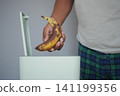 Disposing of a overripe banana in a trash bin 141199356