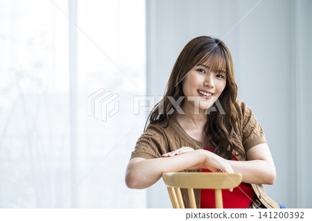Portrait of a young woman sitting on a chair Portrait of a young woman sitting on a chair 141200392