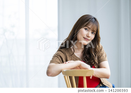 Portrait of a young woman sitting on a chair Portrait of a young woman sitting on a chair 141200393