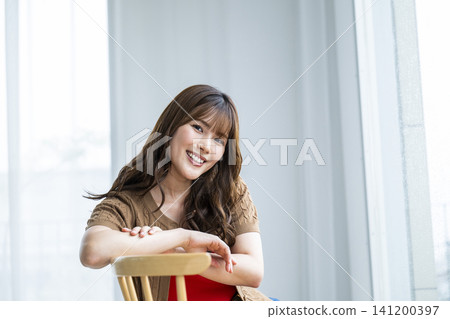 Portrait of a young woman sitting on a chair Portrait of a young woman sitting on a chair 141200397