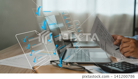 User review a paper form beside a laptop on a desk with digital checklist icons, showing document checking and quality control workflow for audit, approval, and business record review. User review a paper form beside a laptop on a desk with digital checklist icons, showing document checking and quality control workflow for audit, approval, and business record review. 141200786