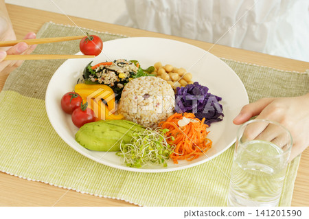 A close-up of a young Japanese woman's hands as she eats a healthy one-plate meal. A close-up of a young Japanese woman's hands as she eats a healthy one-plate meal. 141201590