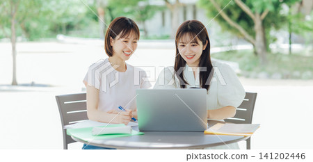 Two female university students using their laptops on the university terrace Two female university students using their laptops on the university terrace 141202446