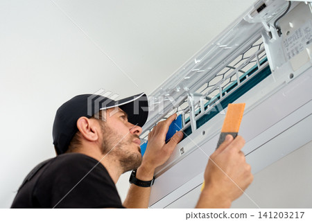 Man cleaning air conditioner filter during home maintenance Man cleaning air conditioner filter during home maintenance 141203217