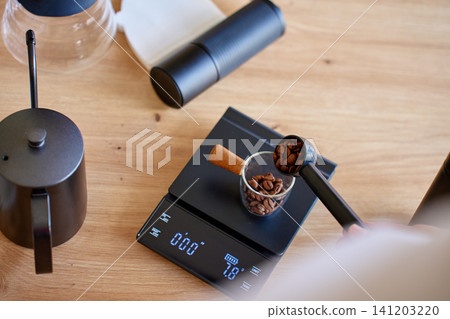 Measuring roasted coffee beans on digital scale for brewing Measuring roasted coffee beans on digital scale for brewing 141203220