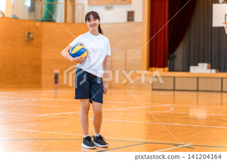 Junior high and high school girls in gym clothes holding volleyballs in the gymnasium. Junior high and high school girls in gym clothes holding volleyballs in the gymnasium. 141204164