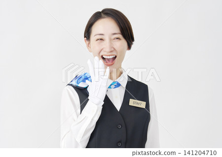 一位面帶微笑、略帶驚訝的女工作人員(接待員/巴士導遊)站在白色背景上。 一位面帶微笑、略帶驚訝的女工作人員(接待員/巴士導遊)站在白色背景上。 141204710