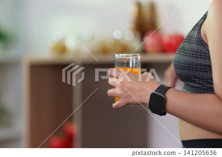 Cropped hand holding glass of orange juice for healthy nutrition and hydration Cropped hand holding glass of orange juice for healthy nutrition and hydration 141205636