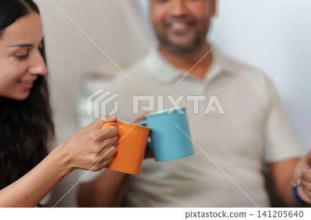 Indian couple clinking coffee mugs celebrating small business success at home Indian couple clinking coffee mugs celebrating small business success at home 141205640